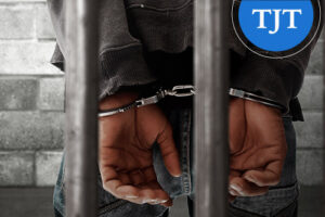 Person in handcuffs behind jail bars, representing a disorderly persons conviction that may qualify for expungement in New Jersey