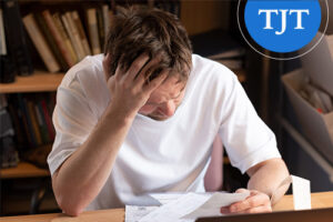 Young man stressed while reviewing paperwork, representing the impact of an old drug conviction that may qualify for young drug offender expungement in New Jersey
