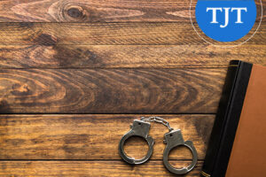 Handcuffs beside a law book on a wooden table, representing expungement of indictable convictions under N.J.S.A. 2C:52-2